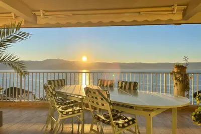 a table and chairs on a balcony with a view of the ocean at Beautiful T4 apt with a view of the Gulf d'Ajaccio in Ajaccio