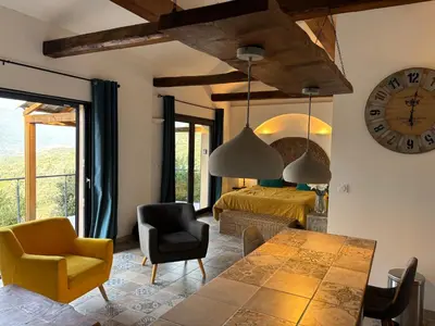 a living room with a table and a clock on the wall at Casa Lisandru- Mini-Villa proche des plages in Viggianello