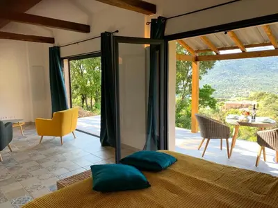 a bedroom with a bed with a view of a patio at Casa Lisandru- Mini-Villa proche des plages in Viggianello