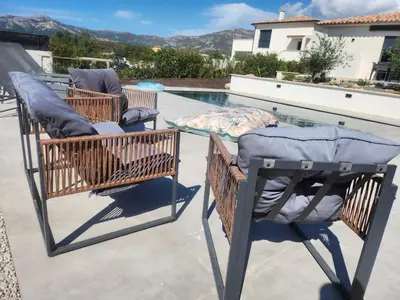 two chairs on a patio next to a swimming pool at Villa DIMA - piscine chauffée climatisation barbecue pétanque in Calenzana