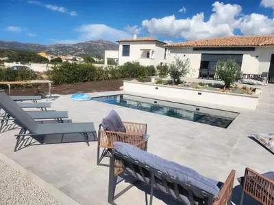 a patio with chairs and a swimming pool at Villa DIMA - piscine chauffée climatisation barbecue pétanque in Calenzana