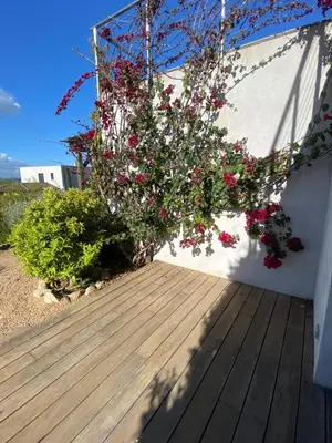 a wooden deck with flowers on the side of a building at Rondinara Camara - Lecci Lodge in Lecci