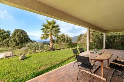 a porch with a wooden table and chairs on a patio at Mare e Machja - Maison avec piscine in Cauro