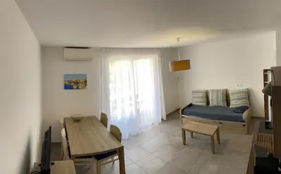 a living room with a couch and a table at Villa résidence avec piscine chauffée Bonifacio in Bonifacio