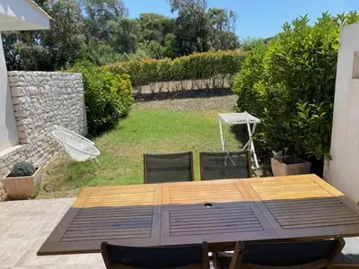 a wooden table and chairs on a patio at Villa résidence avec piscine chauffée Bonifacio in Bonifacio