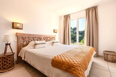a bedroom with a bed and a large window at Casa Vinti - Vue mer et montagne climatisé in Porticcio