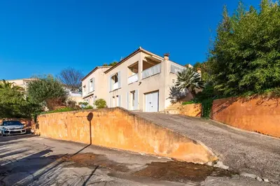 a large white house with a fence in front of it at Casa Vinti - Vue mer et montagne climatisé in Porticcio