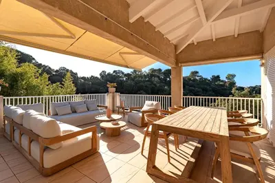 an outdoor patio with a wooden table and chairs at Casa Vinti - Vue mer et montagne climatisé in Porticcio