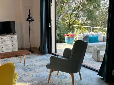 a living room with a chair and a sliding glass door at Casa Lesia - Mini-Villa proche des plages in Viggianello