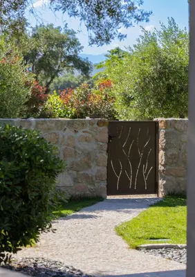 a gate into a garden with a stone wall at Villa Les Granges Classé 5 Étoiles in Antisanti