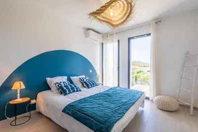 a bedroom with a large bed with a blue headboard at VILLA BAIA 4-5 pers - 2mn plages - Kids Friendly - Clim - Piscine in Lecci
