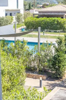 a swimming pool with trees and bushes next to a building at VILLA BAIA 4-5 pers - 2mn plages - Kids Friendly - Clim - Piscine in Lecci