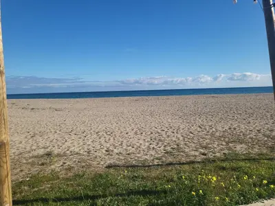 a sandy beach with the ocean in the background at Solenzara T2 rez de villa, vue mer, proximité plage et village in Sari Solenzara