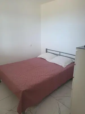a bed with a red blanket and white pillows at Solenzara T2 rez de villa, vue mer, proximité plage et village in Sari Solenzara