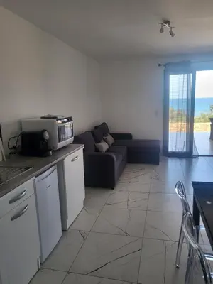 a living room with a couch and a kitchen at Solenzara T2 rez de villa, vue mer, proximité plage et village in Sari Solenzara