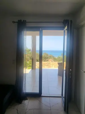 an open door with a view of the ocean at Solenzara T2 rez de villa, vue mer, proximité plage et village in Sari Solenzara
