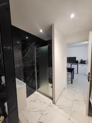 a bathroom with a glass shower with a black wall at Solenzara T2 rez de villa, vue mer, proximité plage et village in Sari Solenzara