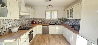 a white kitchen with white cabinets and wooden floors at Spacieux haut de villa 3 chambres Venaco in Venaco
