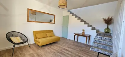 a living room with a chair and a mirror at Spacieux haut de villa 3 chambres Venaco in Venaco