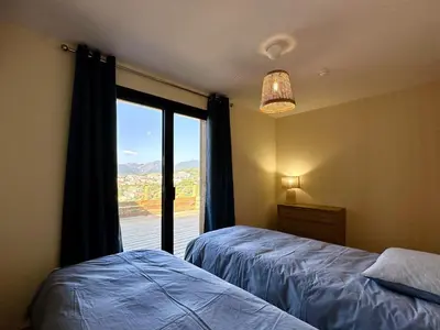 a bedroom with two beds and a window with a view at Superbe vue Mer et Montagne - T3 - 5mn des plages in Propriano