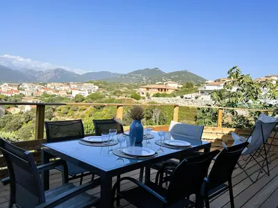 a table and chairs on a deck with a view at Superbe vue Mer et Montagne - T3 - 5mn des plages in Propriano