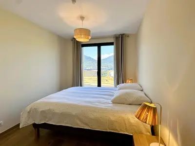 a bedroom with a bed with a window and two lamps at Superbe vue Mer et Montagne - T3 - 5mn des plages in Propriano