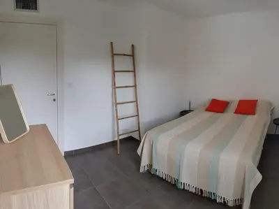 a bedroom with a bed with two red pillows on it at PORTICCIO Appart 6pers Climatisé proche plage in Porticcio