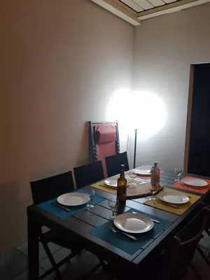 a table with plates and a bottle of wine on it at PORTICCIO Appart 6pers Climatisé proche plage in Porticcio