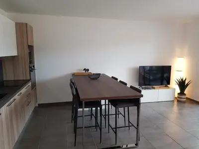 a kitchen with a wooden table and chairs and a television at PORTICCIO Appart 6pers Climatisé proche plage in Porticcio