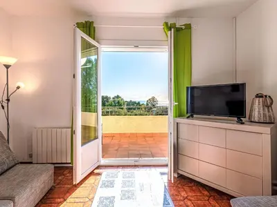a living room with a tv and a sliding glass door at Apartment T3 Gabriello by Interhome in Cala dʼOro