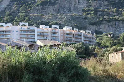 a large white apartment building on a mountain at Beau studio Routes des Sanguinaires proche de la plage in Ajaccio