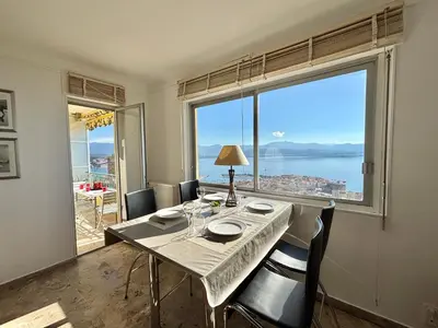 a dining room with a table and a large window at Appartement Parc Belvédère Ajaccio in Ajaccio