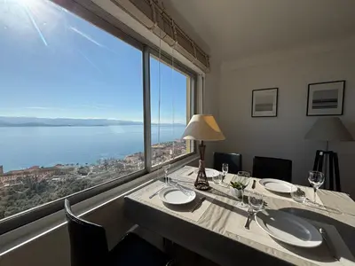 a dining room with a table with a large window at Appartement Parc Belvédère Ajaccio in Ajaccio