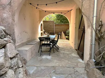 a patio with a table and chairs in an archway at Mini-villa à 5 minutes de la plage de Santa Giulia in Porto-Vecchio