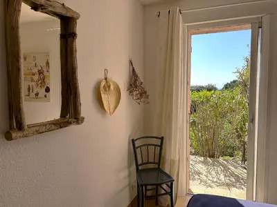 a bedroom with a mirror and a chair next to a door at Mini-villa à 5 minutes de la plage de Santa Giulia in Porto-Vecchio