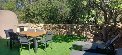 a table and chairs in a yard with a stone wall at Porto Vecchio - Résidence RIVIERA- Villa Santa Giulia in Lecci