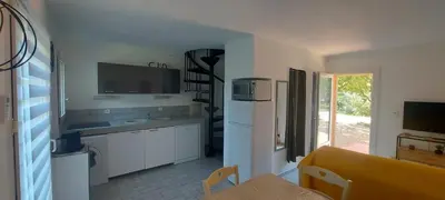 a kitchen with white cabinets and a refrigerator and a table at Porto Vecchio - Résidence RIVIERA- Villa Santa Giulia in Lecci