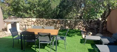 a wooden table and chairs and a stone wall at Porto Vecchio - Résidence RIVIERA- Villa Santa Giulia in Lecci