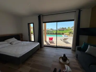 a bedroom with a bed and a sliding glass door at Casa Nostra Villa Récente Climatisée - Piscine Chauffée in Lecci