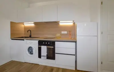 a kitchen with white cabinets and a sink and a dishwasher at Charmant T2 à la campagne in Riventosa