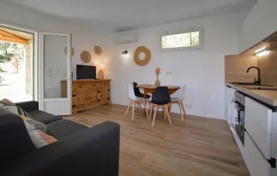 a living room with a couch and a table with chairs at Charmant T2 à la campagne in Riventosa