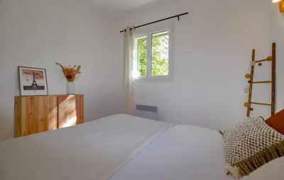 a white bedroom with a bed and a window at Charmant T2 à la campagne in Riventosa