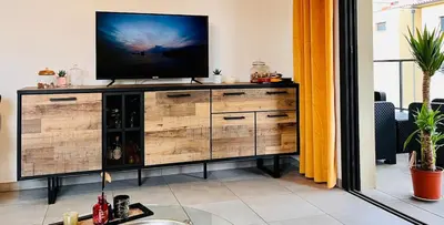 a living room with a television on a wooden dresser at Superbe T3 vue mer in Propriano