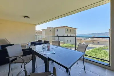 a dining room with a table and chairs and a large window at Superbe T3 vue mer in Propriano