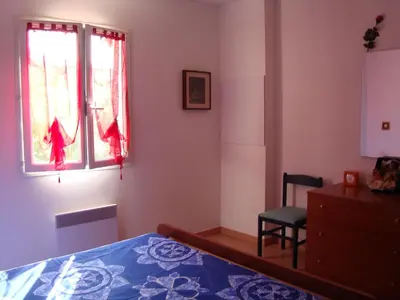a bedroom with a bed and a chair and a window at Villa individuelle avec jardin in Sartène