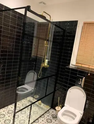 a black tiled bathroom with a toilet and a shower at Villa ALMA in Porto-Vecchio