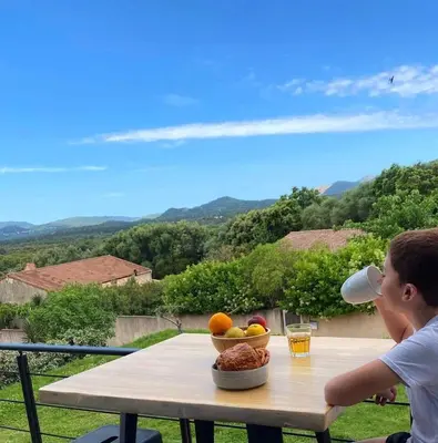 a man drinking a cup of coffee on a table with a bowl of fruit at MaisonDrs in Porto-Vecchio