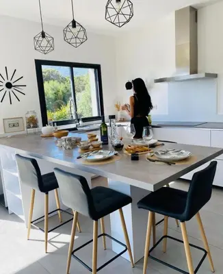 a woman in a kitchen with a table with food on it at MaisonDrs in Porto-Vecchio