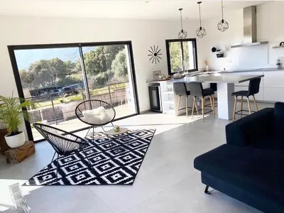 a living room with a couch and a table and a kitchen at MaisonDrs in Porto-Vecchio
