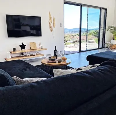 a living room with two black couches and a tv at MaisonDrs in Porto-Vecchio